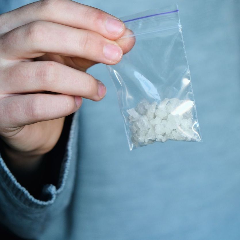 hand holds packet with white narcotic - cocaine, meth or another drug