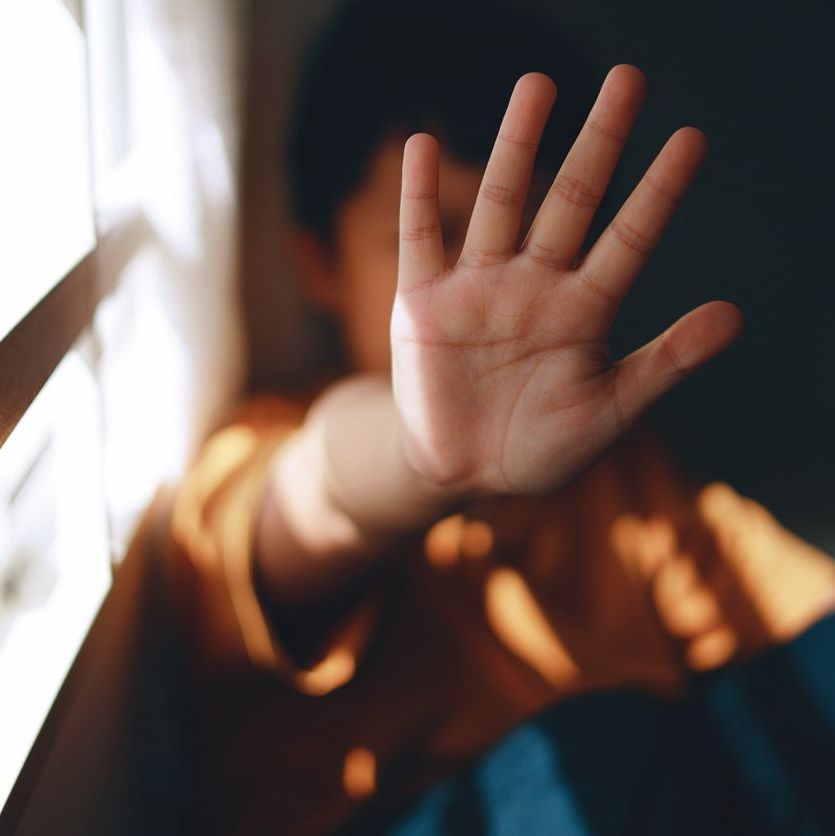 A young boy is screaming and holding his palm open in a stop gesture to counteract bullying