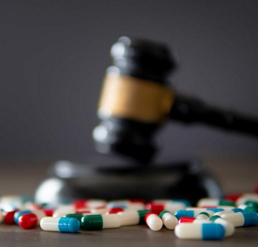 Closeup image of colorful medicine pills and judge gavel on table.