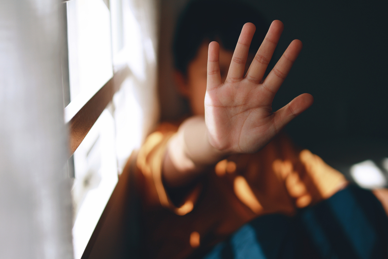 A young boy is screaming and holding his palm open in a stop gesture to counteract bullying