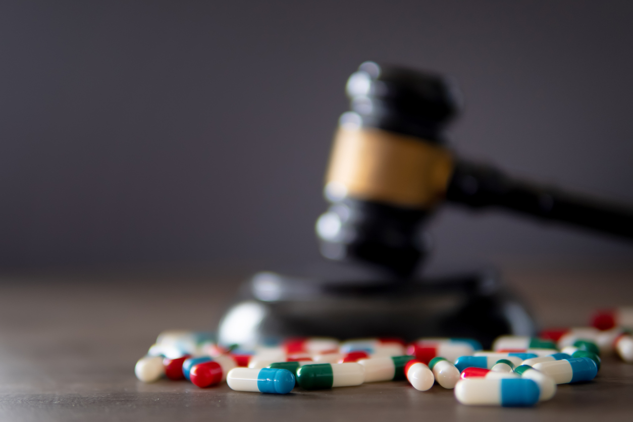 Closeup image of colorful medicine pills and judge gavel on table.